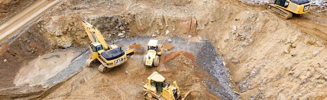 Four heavy equipment on quarry at daytime. Small Business Management Consulting